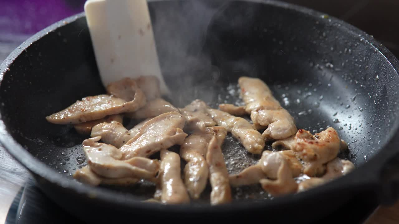 把肉块放在煎锅里煎。在煎锅中用热油煎鸡肉，特写。视频素材