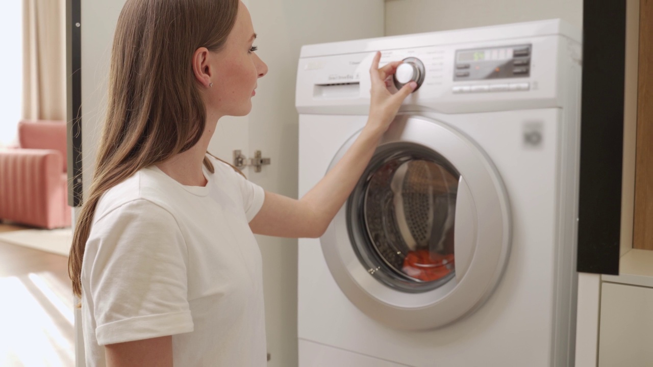 一名妇女把一粒洗衣粉放在洗衣机里的脏衣服上。女人打开洗衣机视频素材