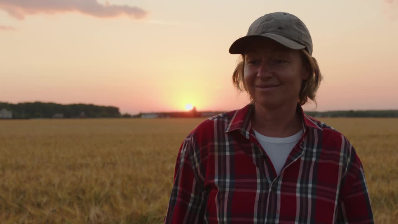 日落时分，快乐的农妇走在麦田里，用手摸着玉米穗。视频素材