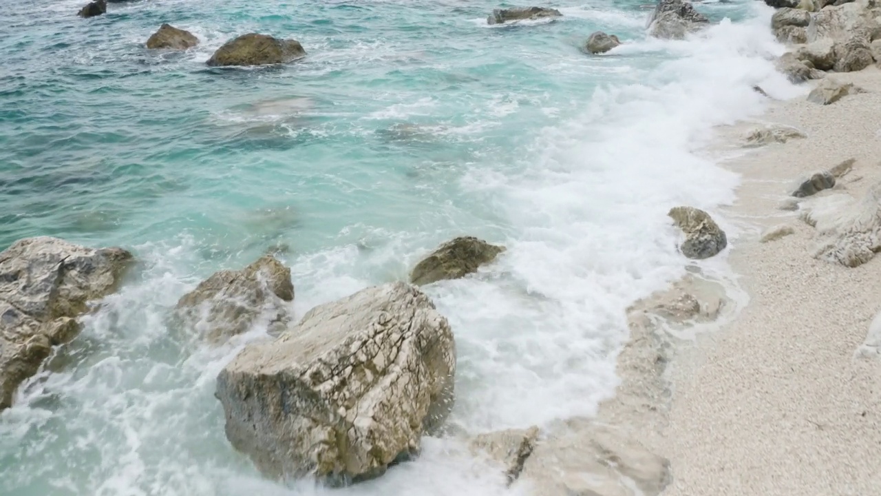 飞越岩石海岸，清澈的蓝绿色海水鸟瞰图夏季海景视频下载