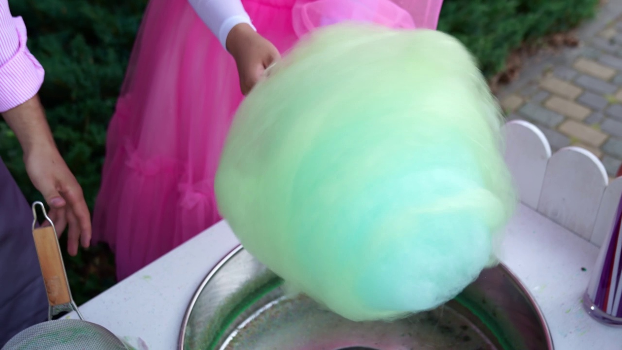 女人的手缠着一根彩色的棉花糖。视频下载