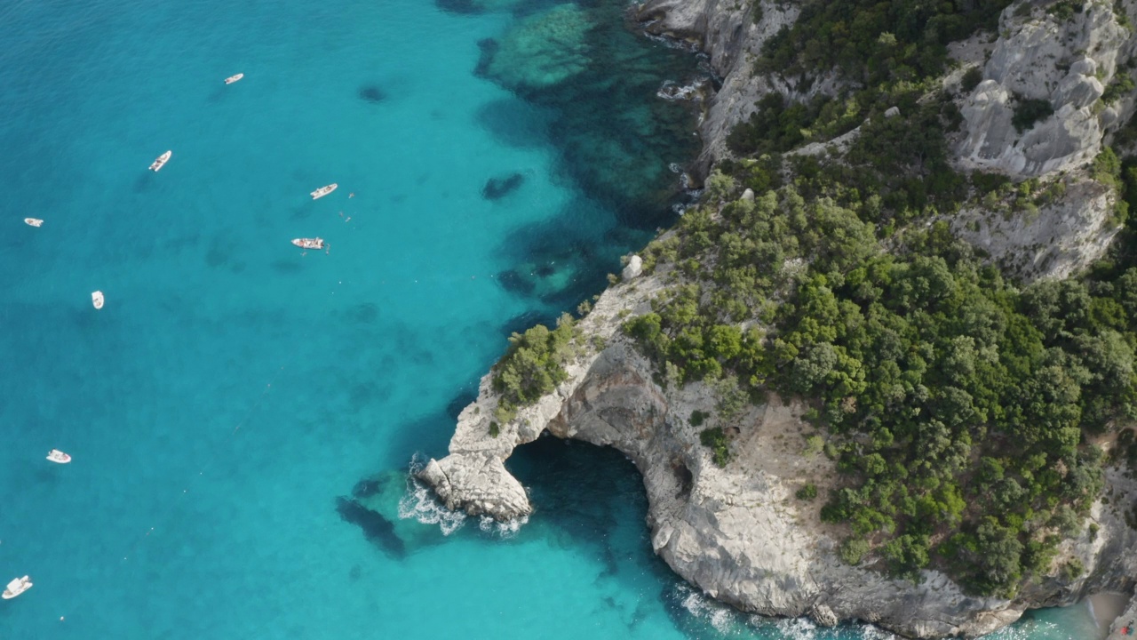 鸟瞰夏季海景，美丽的海洞，清澈的蓝色翡翠水和摩托艇与人休息俯瞰。意大利撒丁岛视频下载