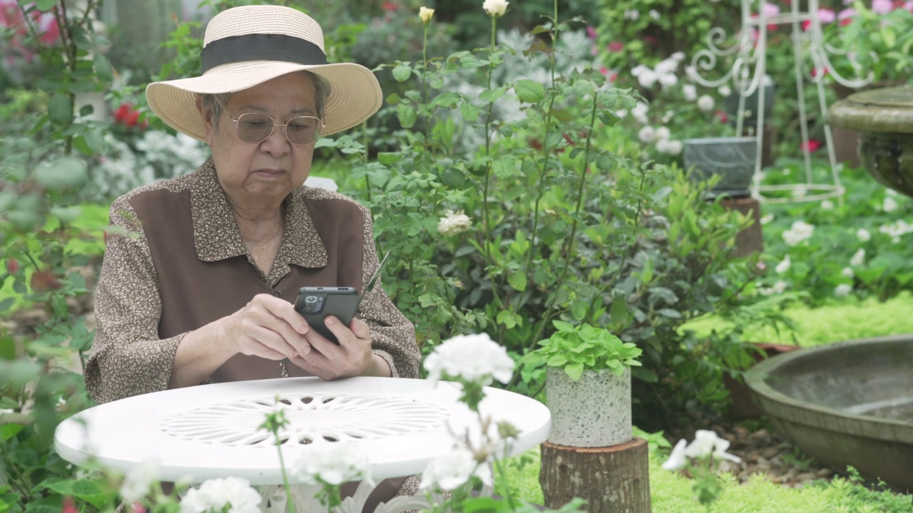 亚洲老年老年老年妇女老年人使用社交媒体的手机智能手机。成熟的退休生活视频素材