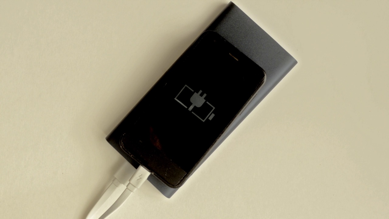 黑色智能手机通过充电宝充电，充电指示灯闪烁。视频下载