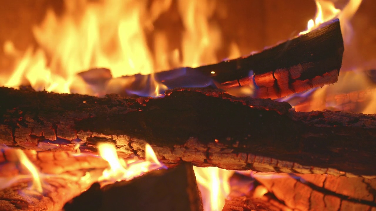 特写，烧焦原木上的火焰。原木在壁炉里燃烧，红色的火焰。舒适放松的壁炉，木柴炉，红色的火。4 k, ProRes视频素材