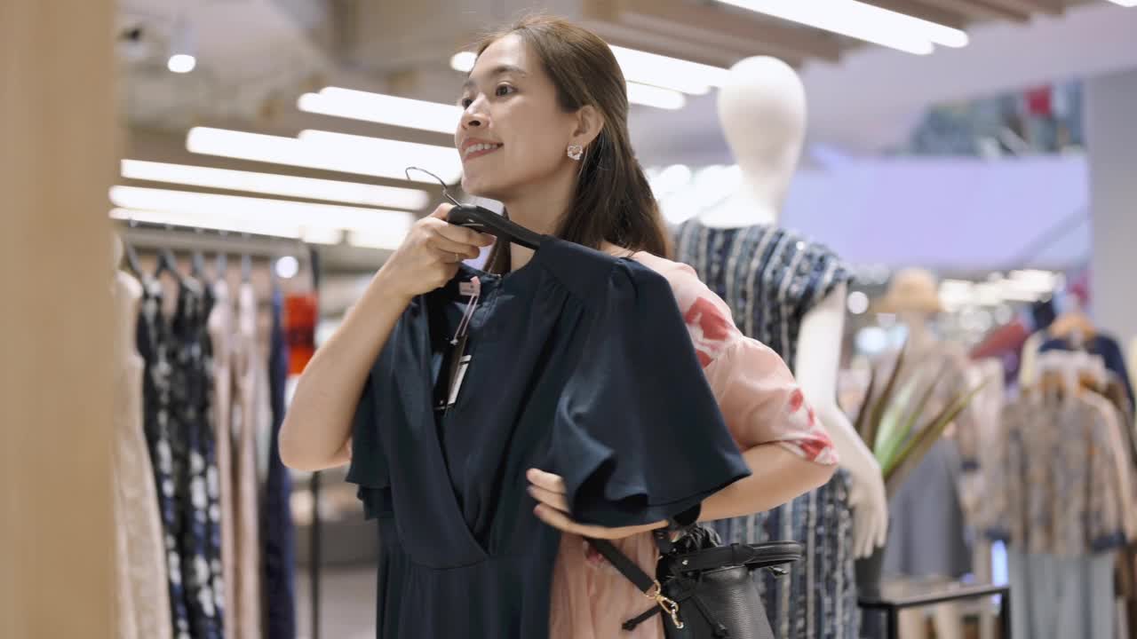 年轻的亚洲在百货公司工作后，穿着简约的衣服购物视频素材