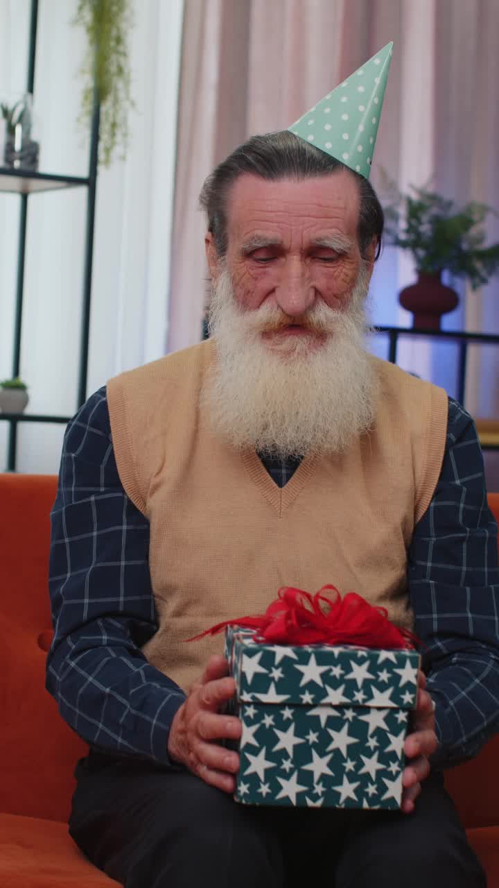 快乐的老年老人拿着带丝带的生日礼盒，庆祝聚会，打开礼物在家里视频素材