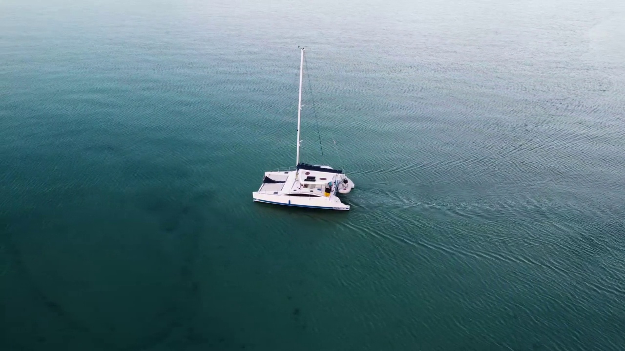 双体船沿着绿松石色的水和岩石海岸线行驶，泰国Koh Kood视频下载