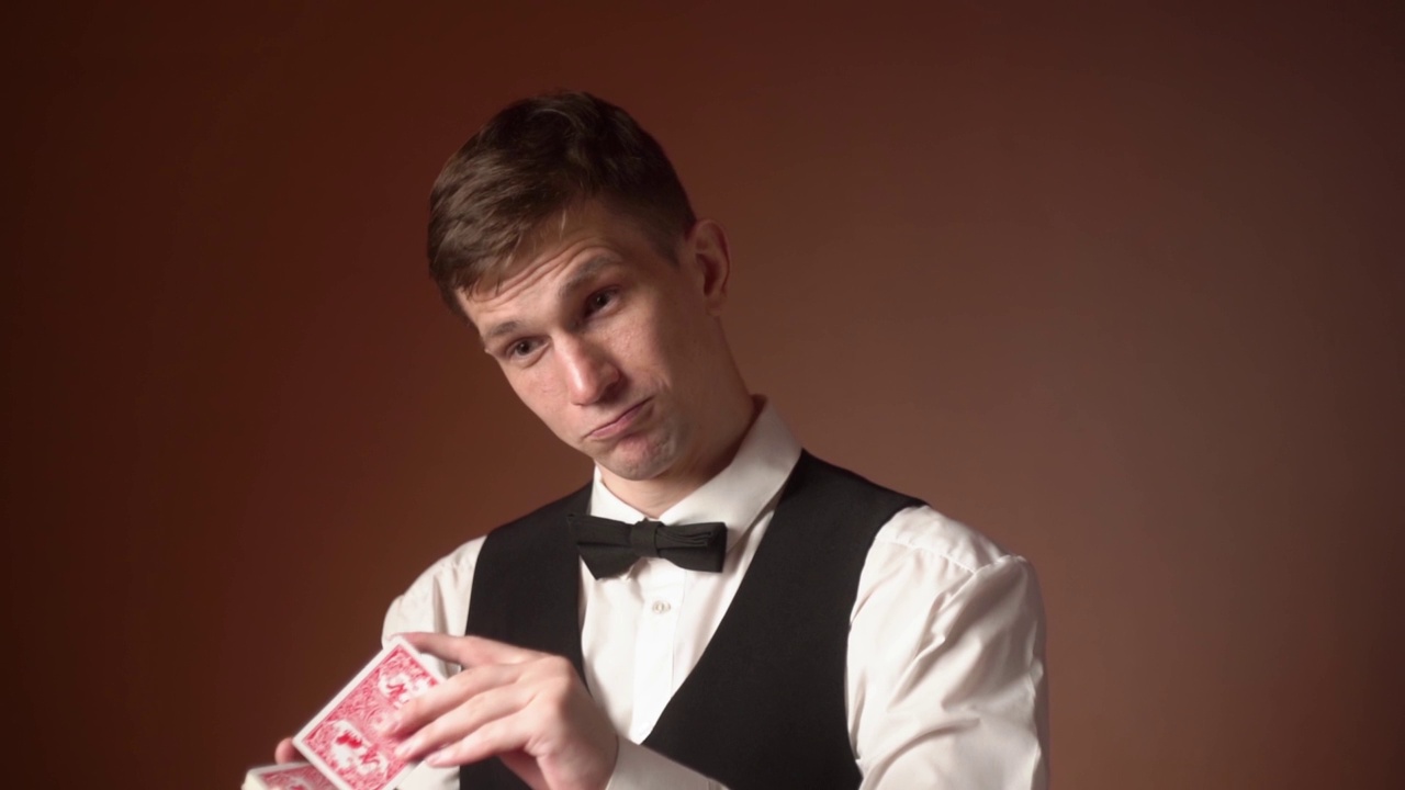 一个年轻的白人男性经销商从一副牌中拿出一张幸运卡的肖像。孤立的视频下载