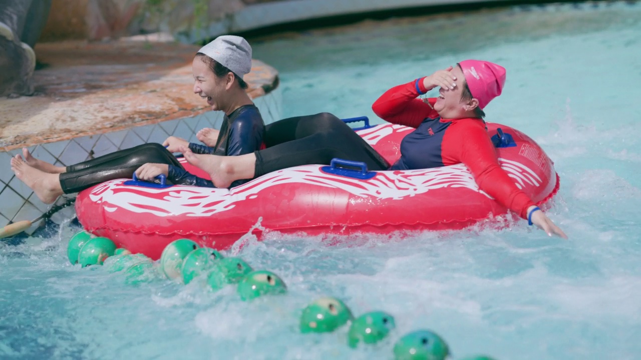 亚洲妇女在水上公园玩滑梯视频素材