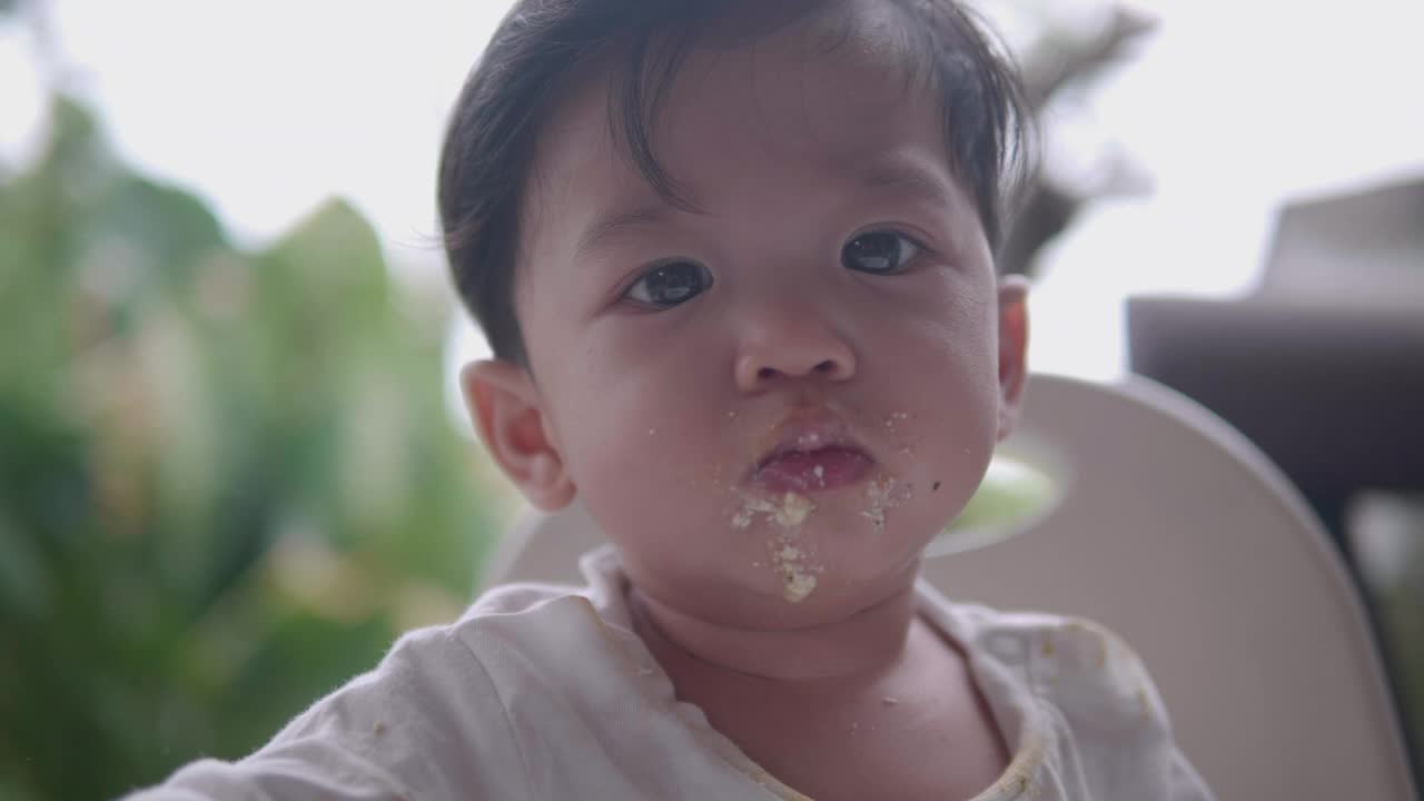 亚洲母亲在家里用勺子喂男婴吃早餐。视频素材