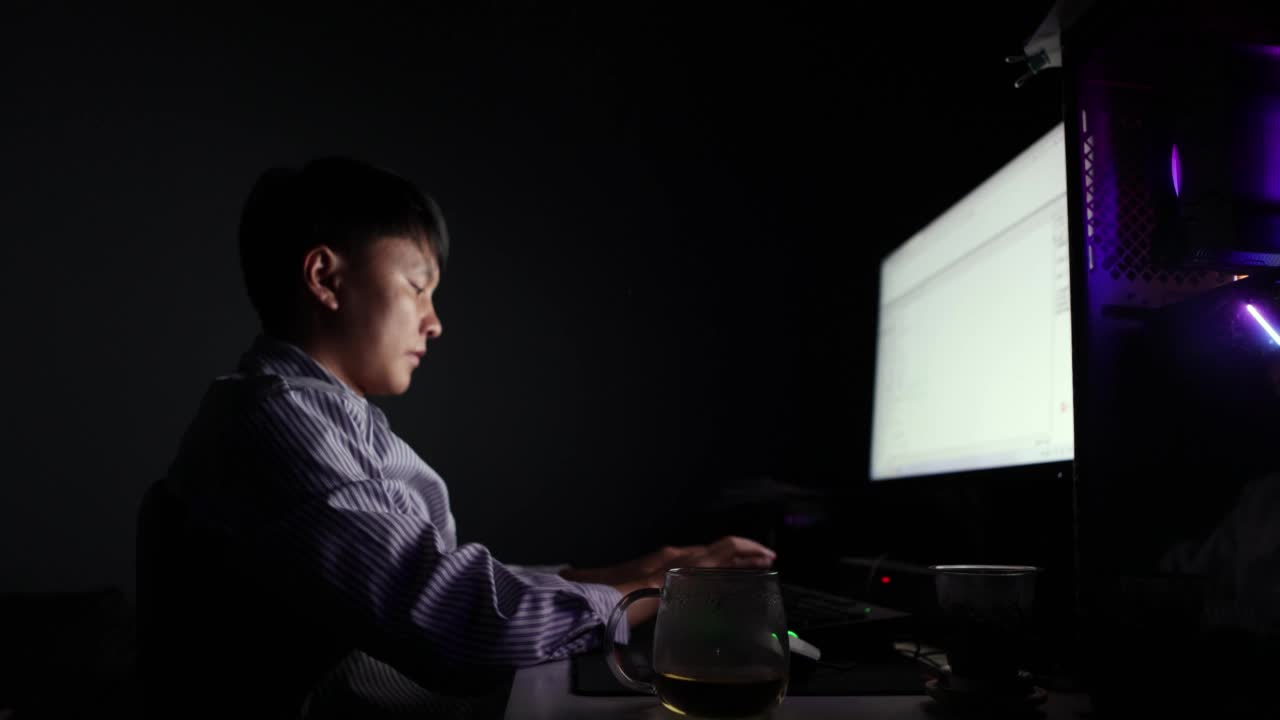 晚上，一位亚洲男子在电脑前伸懒腰，打呵欠——这是年轻人的生活方式视频下载