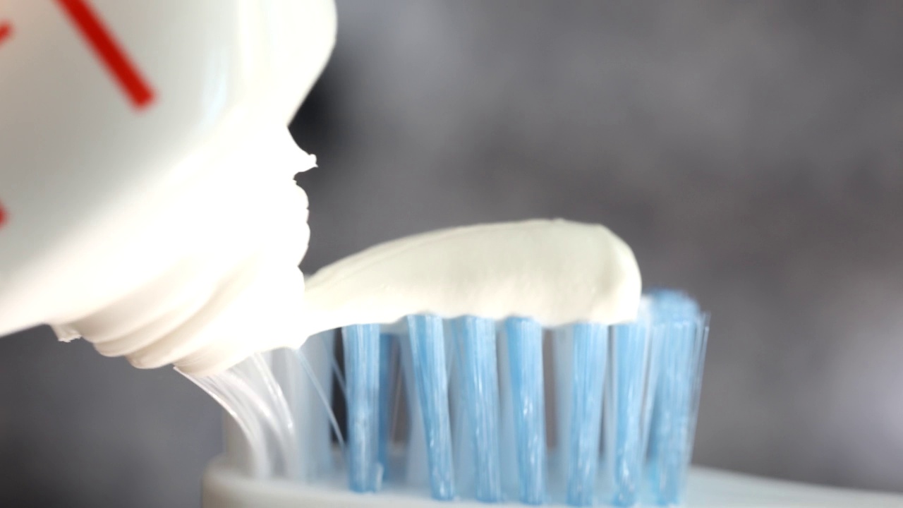 女性将白色牙膏涂在牙刷上视频下载