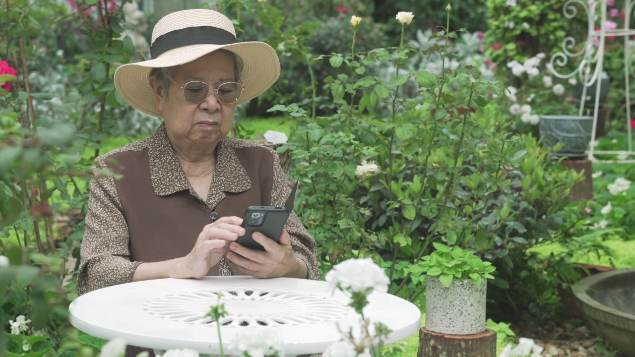亚洲老年老年老年妇女老年人使用社交媒体的手机智能手机。成熟的退休生活视频素材