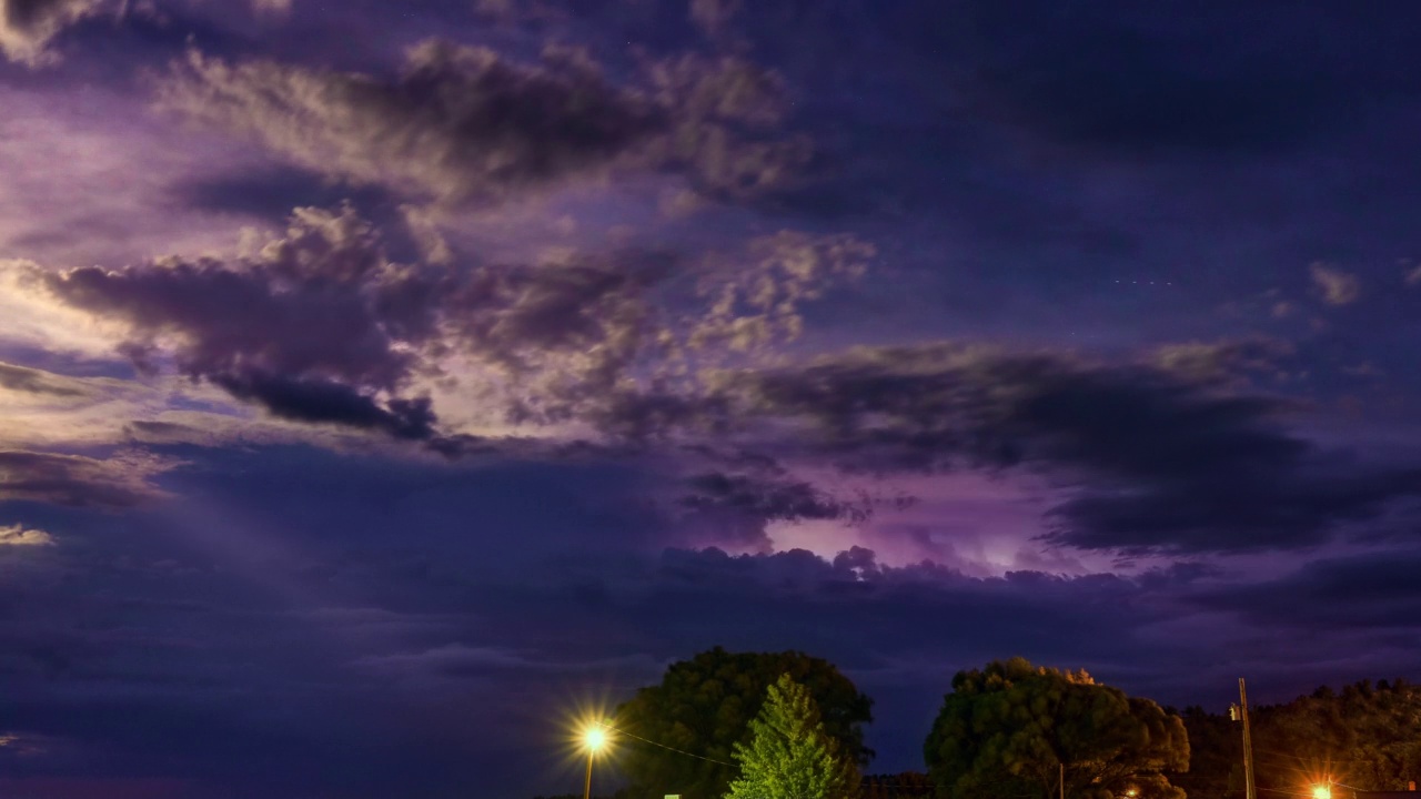 美丽的充满活力的紫色夜空在农村地区。在暴风雨的天空中可见的一连串闪电。时间流逝视频素材
