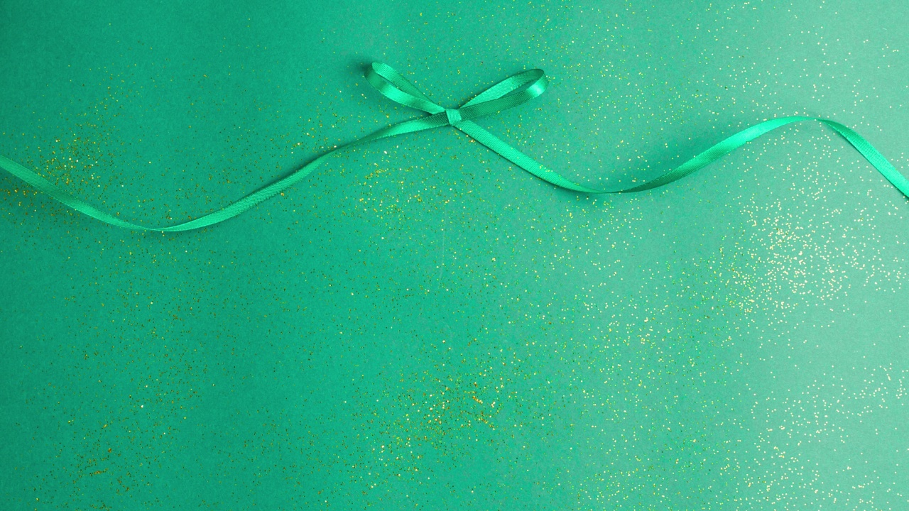 翠绿色缎带蝴蝶结，系和解开的绿色与金色闪光。定格动画圣诞假期和呈现概念平面与复制空间视频下载