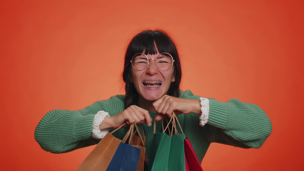 快乐的女游客展示着购物袋，广告假期打折，惊叹于低廉的价格视频素材