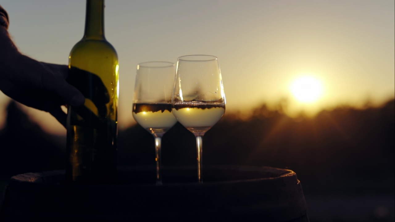 日落时分，一个男人把白葡萄酒倒进玻璃杯里视频下载