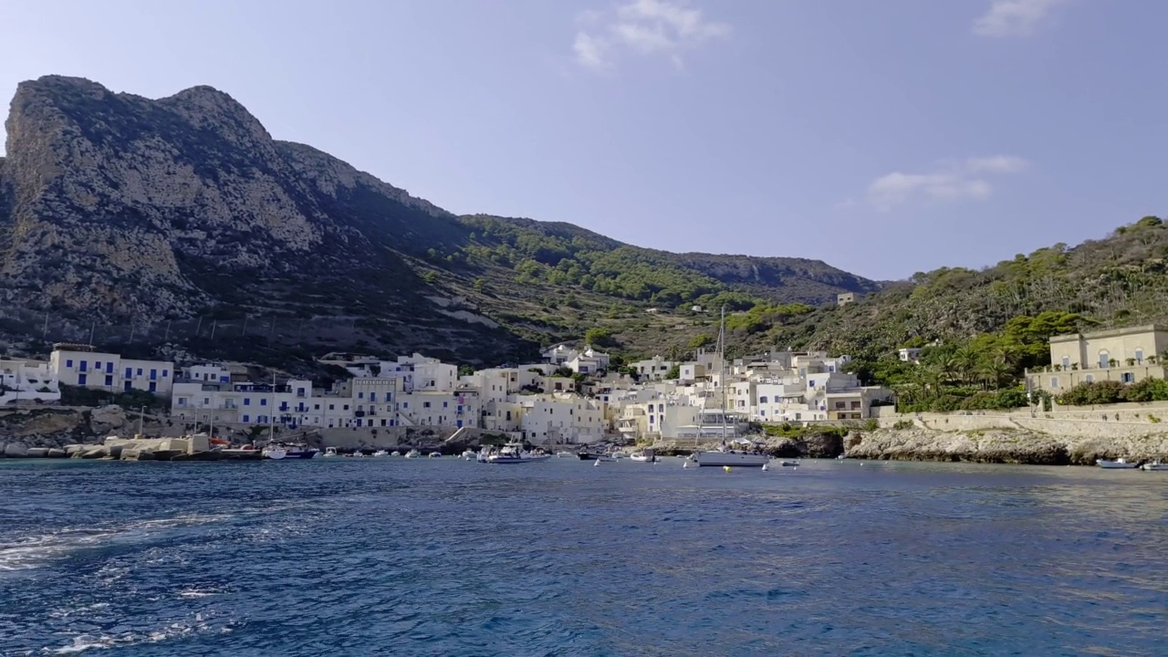 在意大利西西里岛清澈晶莹的地中海上，从船上看到的莱万佐岛和村庄视频下载