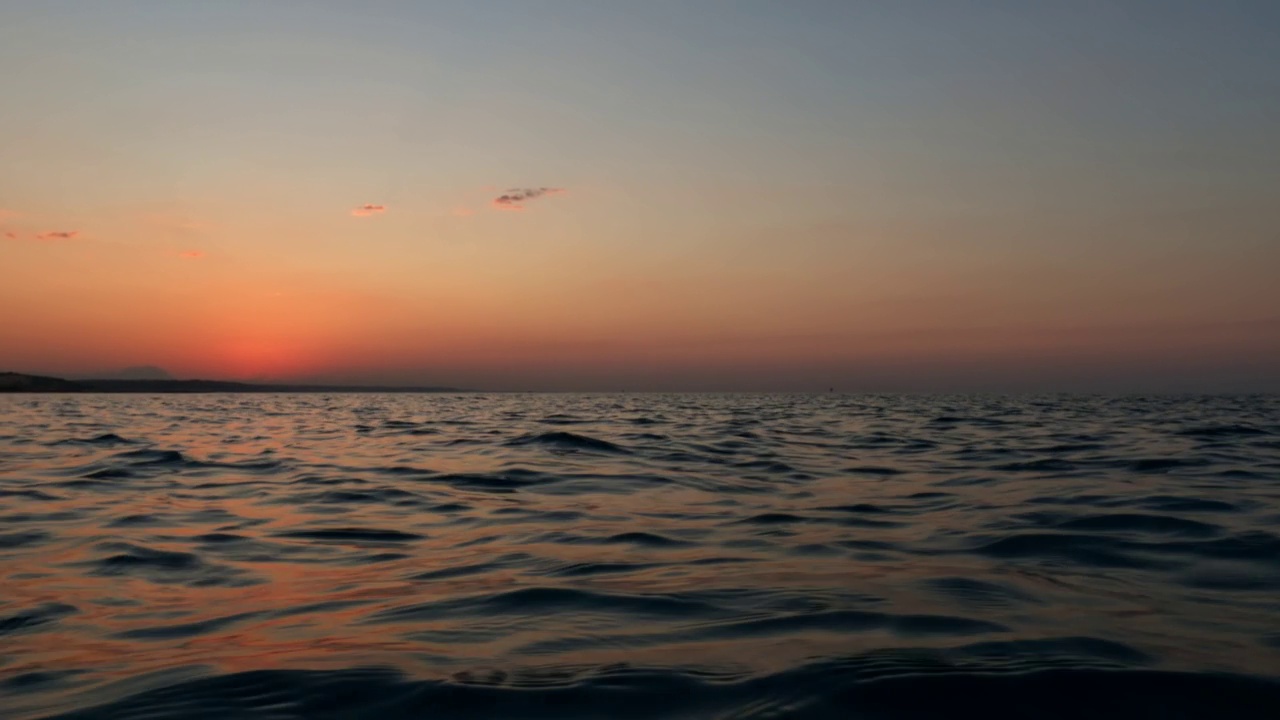 美丽的低角度海平面pov从帆船航行在海水表面在日落。慢动作视频素材