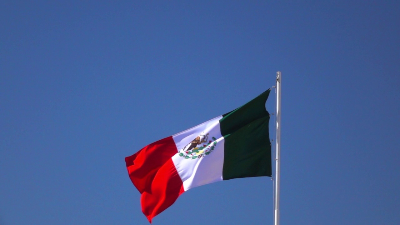 在阳光明媚的日子里，墨西哥国旗在晴朗的天空下挥舞的慢动作镜头——墨西哥的下加利福尼亚州视频下载