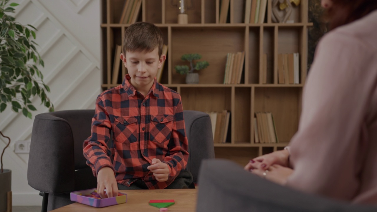 自闭症男孩和自闭症治疗师一起解木头拼图。自闭症谱系障碍教育。视频下载