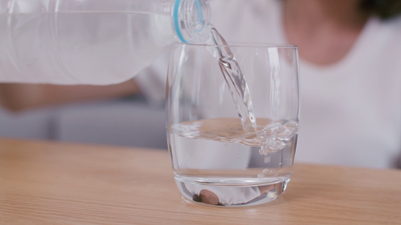 特写女子倒清冷水在一个玻璃杯。视频素材