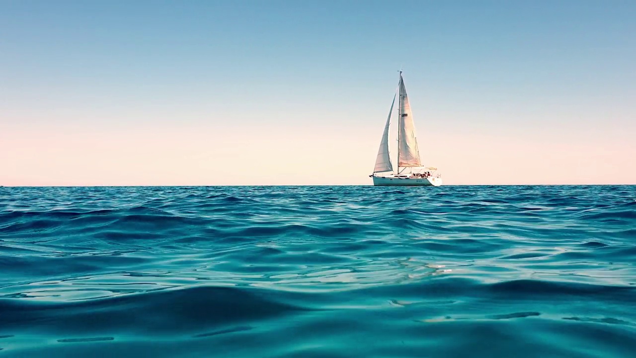从低角度看，白色的小游艇在平静的公海上缓慢航行视频素材