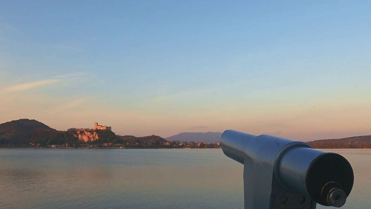 在日落时分，从阿罗那视点观看意大利马乔里湖上的安杰拉城堡的双目望远镜视频素材