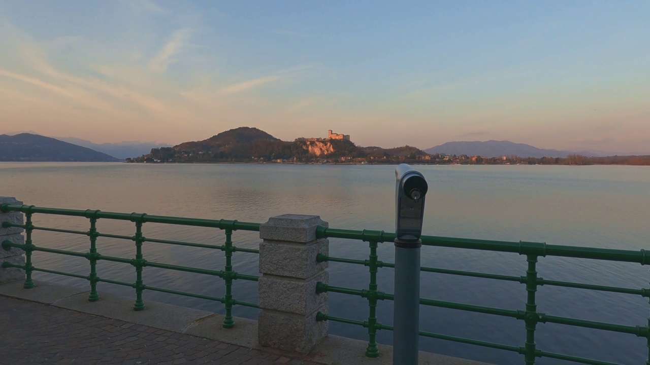 在日落时分，从阿罗那视点向望远镜的第一人称视角指向意大利马乔里湖上的安杰拉城堡视频素材