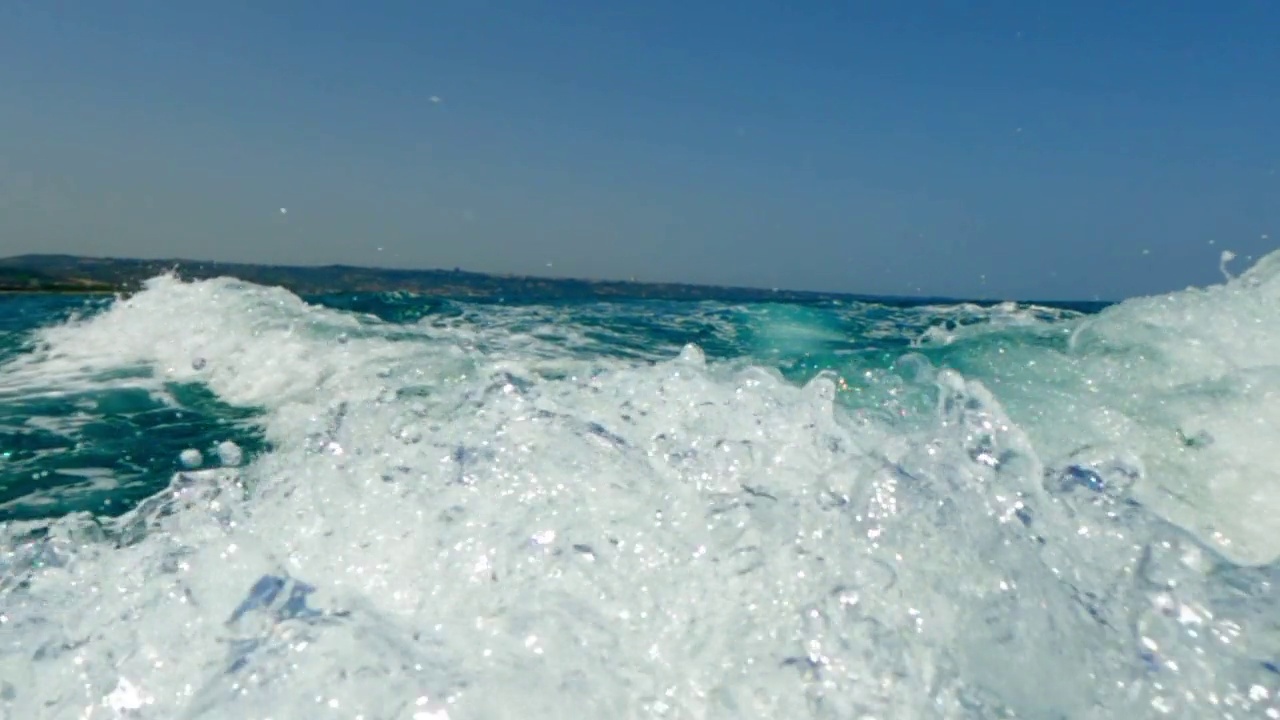 摩托艇尾迹在蓝色海水上的低角度水面pov。慢动作视频素材