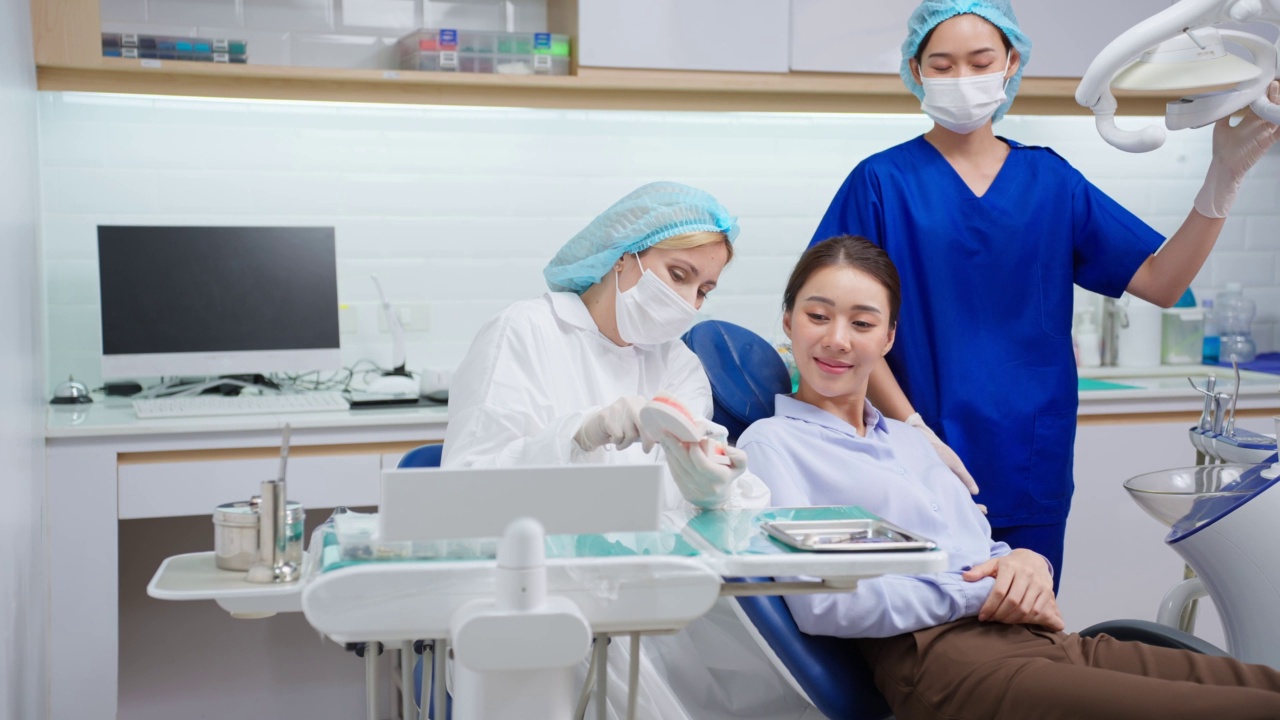 牙科医生在牙科诊所向病人讲解口腔护理及刷牙。美丽的女病人躺在牙科椅上，在医院的预约服务中接受医生的牙科治疗。视频下载