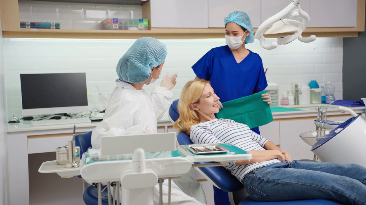 女牙医在牙科诊所为白人女孩检查牙齿。美丽的女病人躺在牙科椅上，在医院的预约服务中接受医生的牙科治疗视频下载