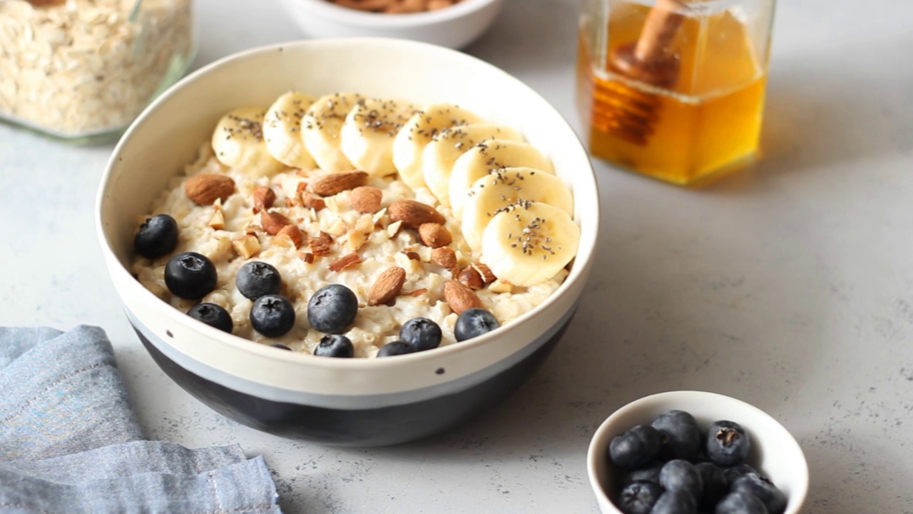 燕麦配香蕉，蓝莓，杏仁和蜂蜜。健康食品。素食。早餐。视频素材