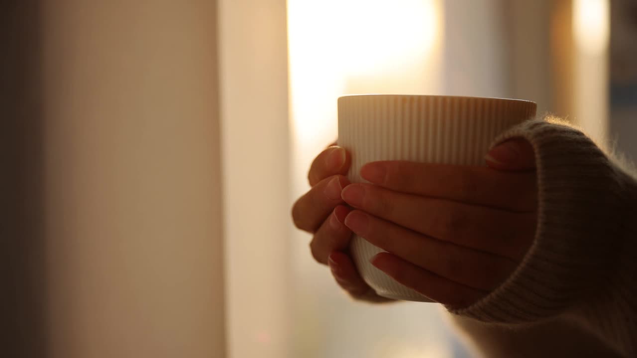 清晨，女性手捧着一杯热咖啡视频素材