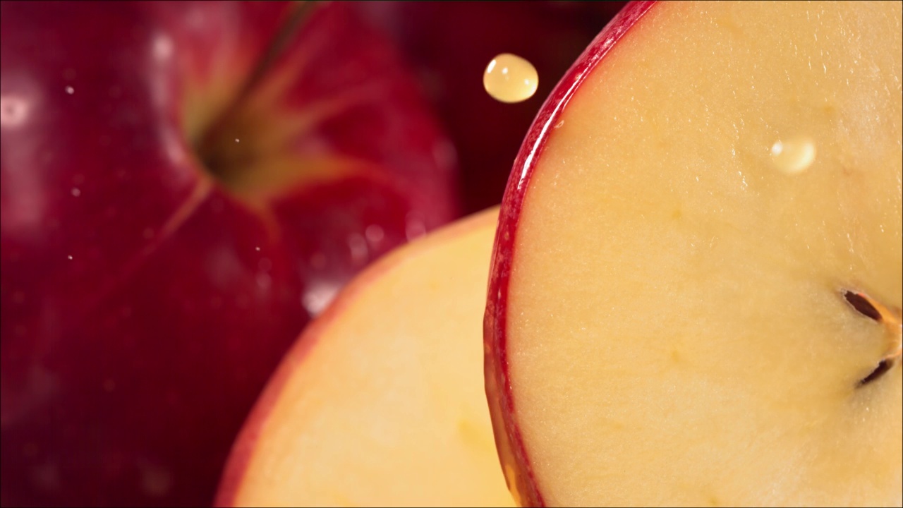 一滴果汁顺着成熟多汁的红苹果片的表面流下来。慢镜头4 k视频素材
