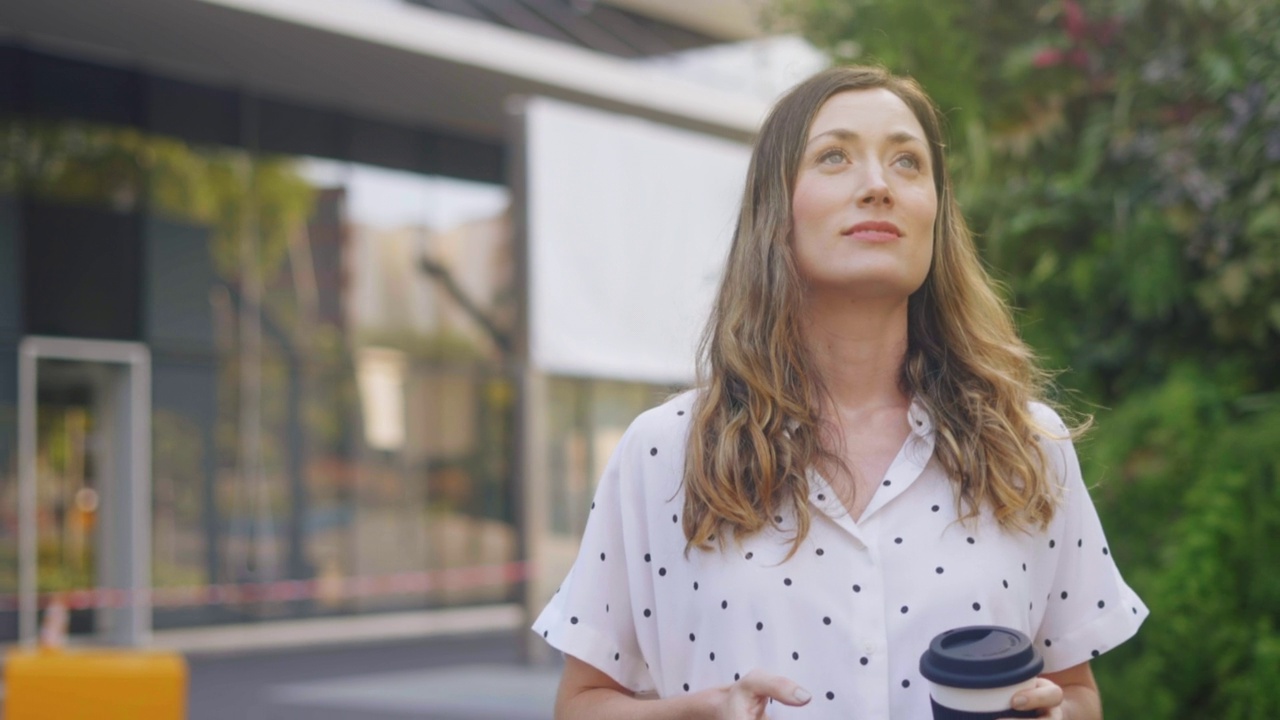 商务女性使用智能手机和喝咖啡在路上视频素材