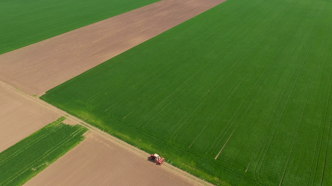 带播种机的拖拉机在田间的无人机，农业机械在栽培种植园之间的土路上视频素材
