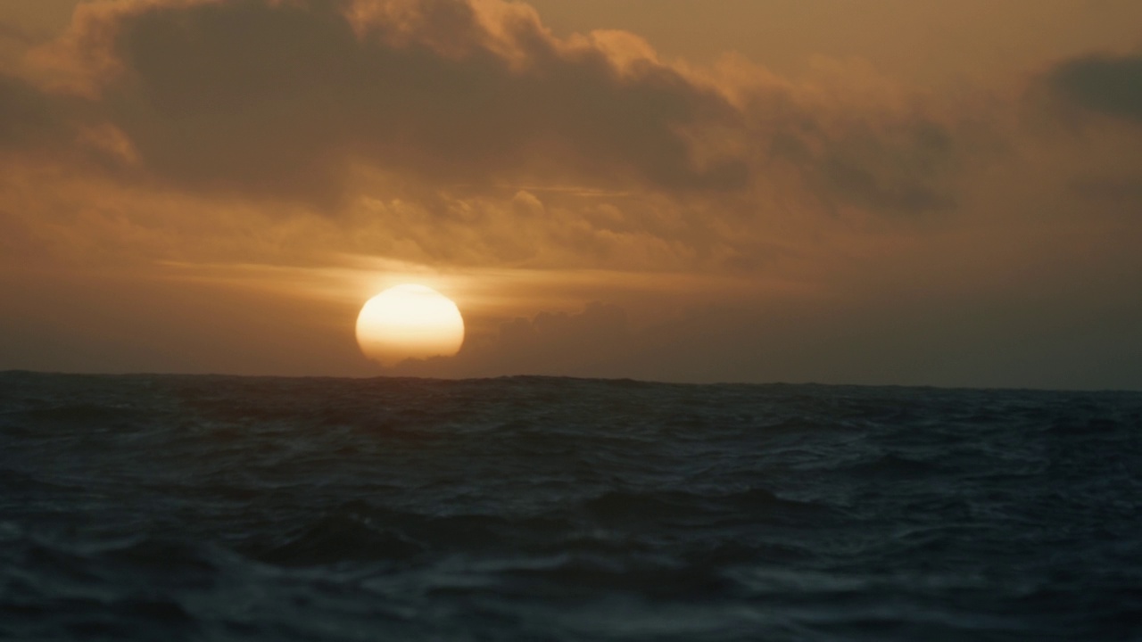 夕阳落在波涛汹涌的海面上，从一艘小船上驶过开阔的大海视频素材
