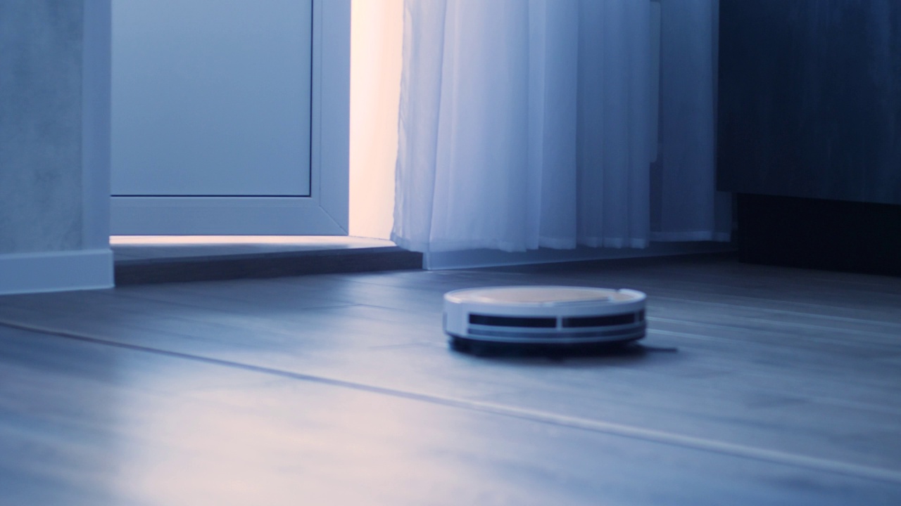 吸尘器机器人在公寓的地板上移动清洁。帮助人们日常生活的技术。用智能机器人吸尘器打扫房子视频素材