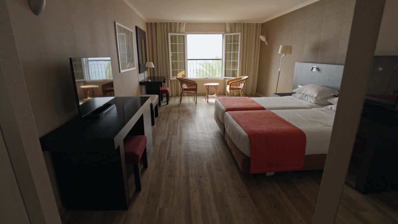 床，桌子和两把椅子在经典的酒店房间。舒适的放松场所。镜头移到度假酒店的空房间上。常平架枪视频下载