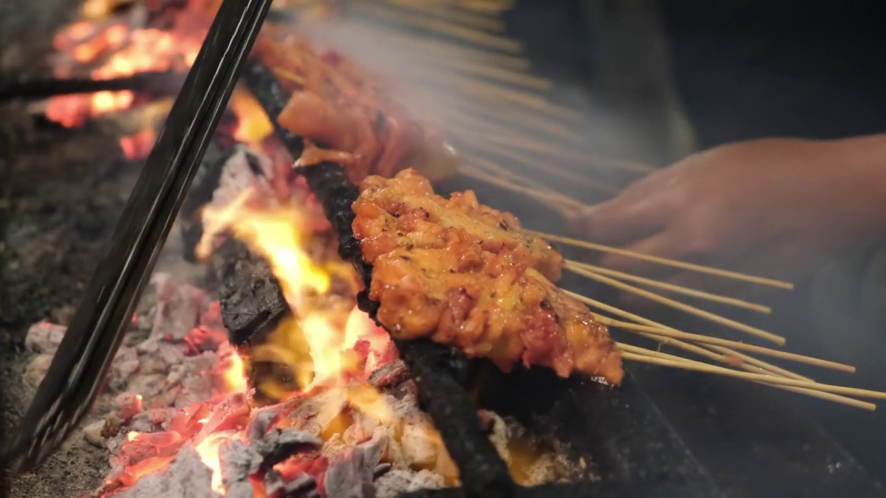 烤肉串鸡沙爹在炭火烧烤与火焰和烟。视频素材