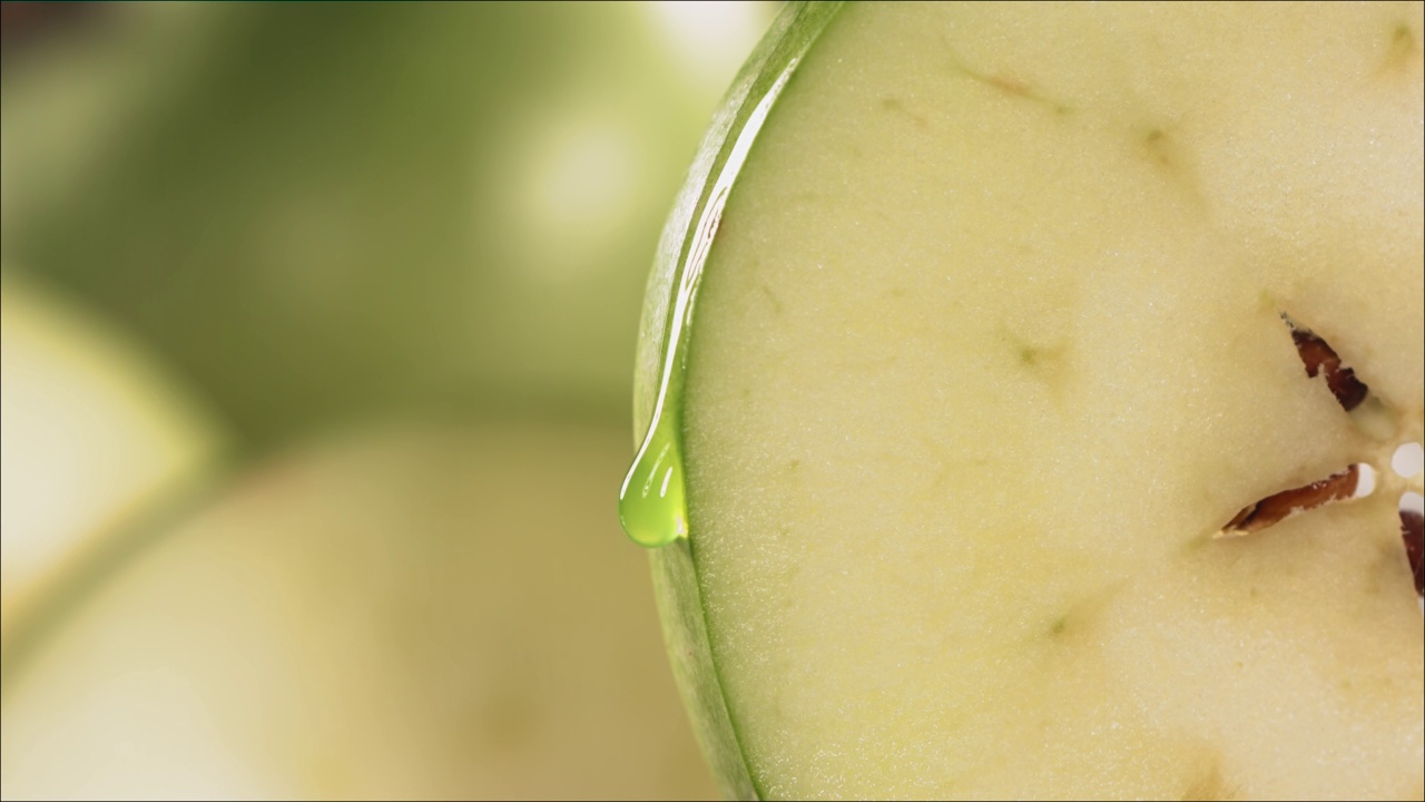 一滴绿汁顺着成熟多汁的青苹果片的表面流下来。慢镜头4 k视频下载
