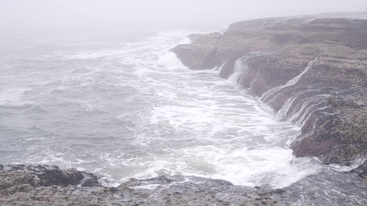 雾蒙蒙的海景，海浪在雾霾中拍打着海滩。暴风雨有雾的天气视频素材