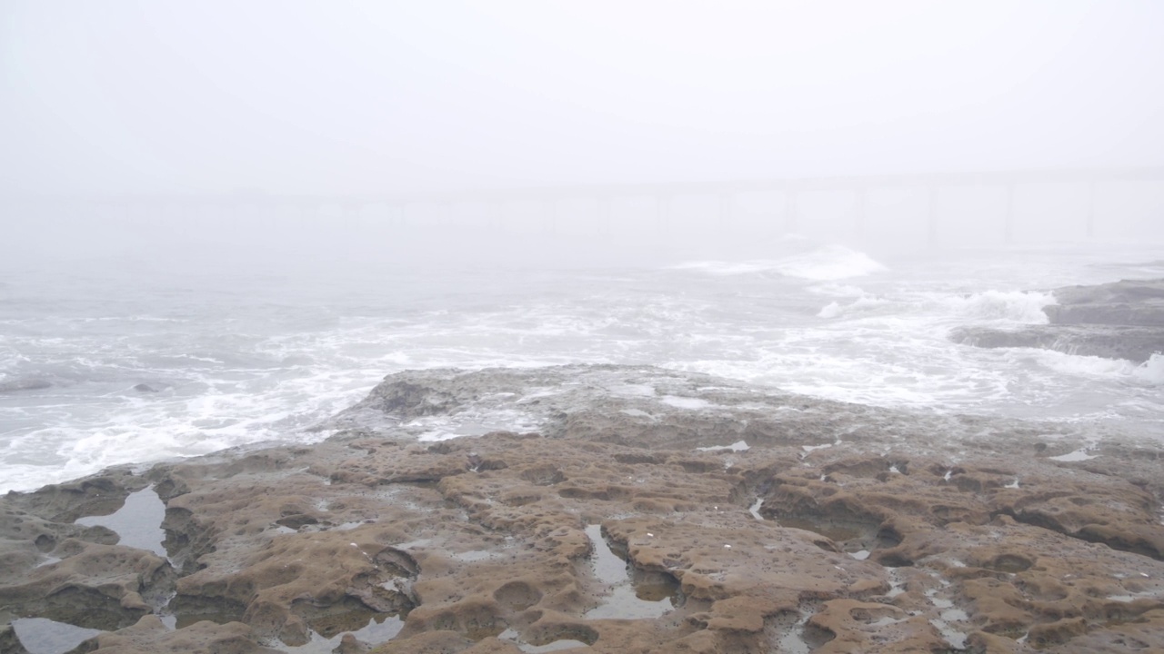 雾蒙蒙的海景，海浪在雾霾中拍打着海滩。暴风雨有雾的天气视频素材
