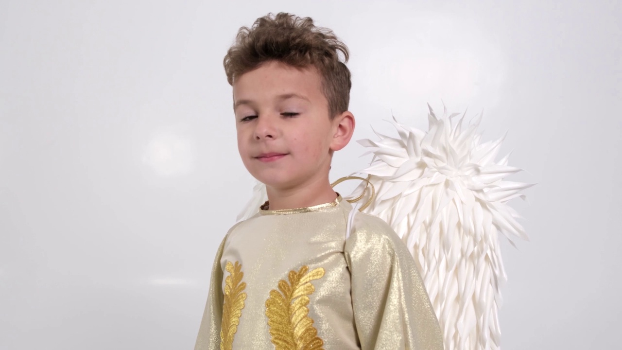 小男孩长着白色天使形状的翅膀，他正在白色的画室里玩耍。视频下载