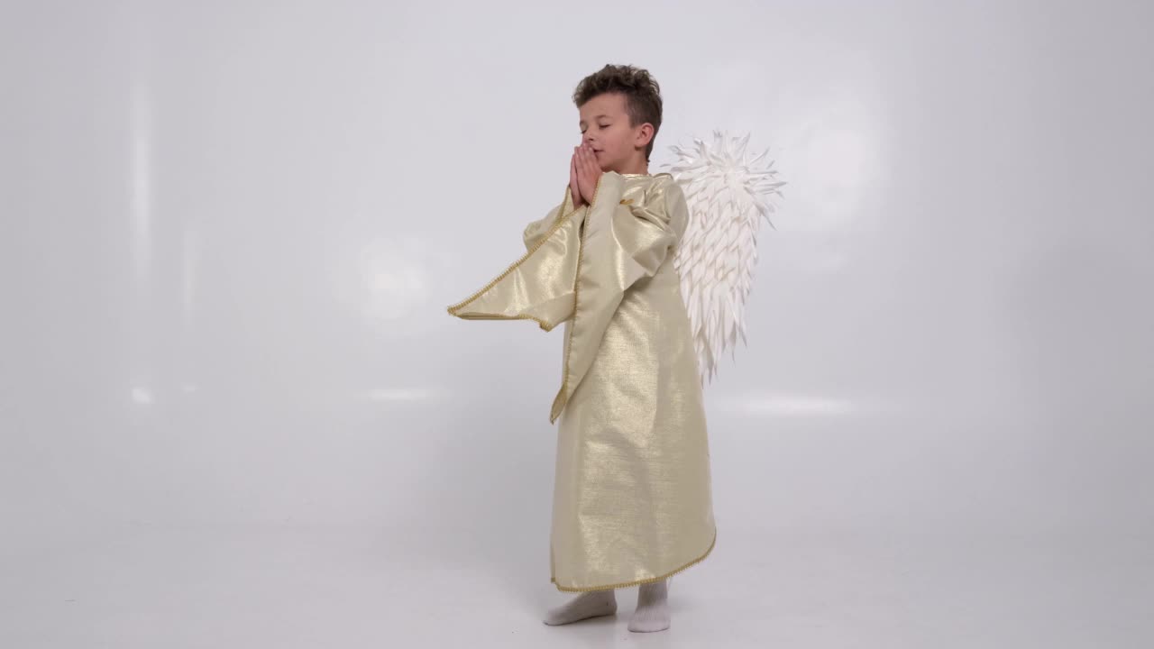 小男孩祈祷他在白色的画室里变成一个有白色翅膀的天使视频下载
