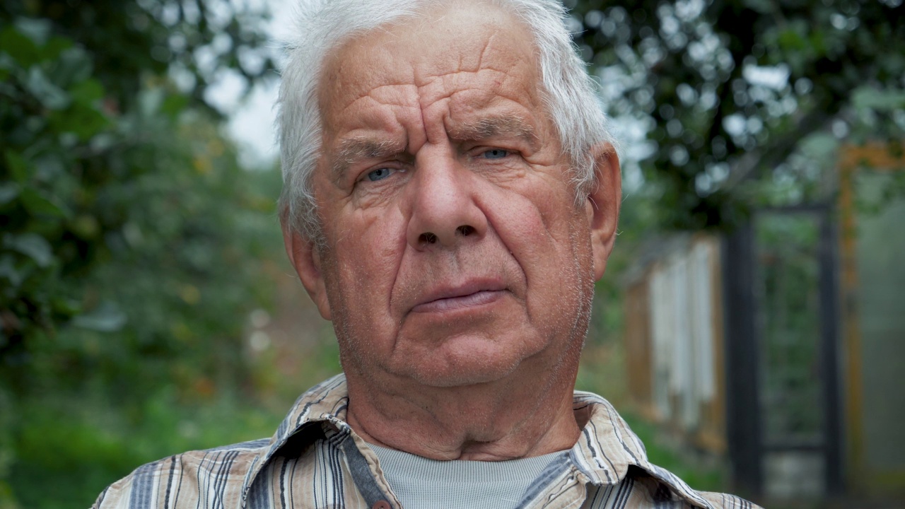 古铜色的老男人的肖像，灰色的头发，蓝色的眼睛看着相机视频下载
