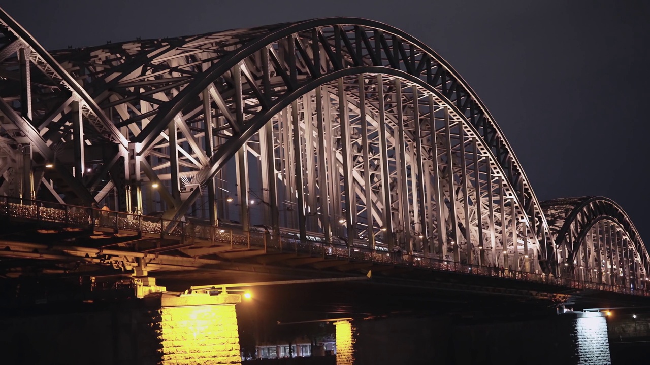 德国科隆的地铁公共交通列车在夜间通过霍亨索伦桥，慢镜头视频下载