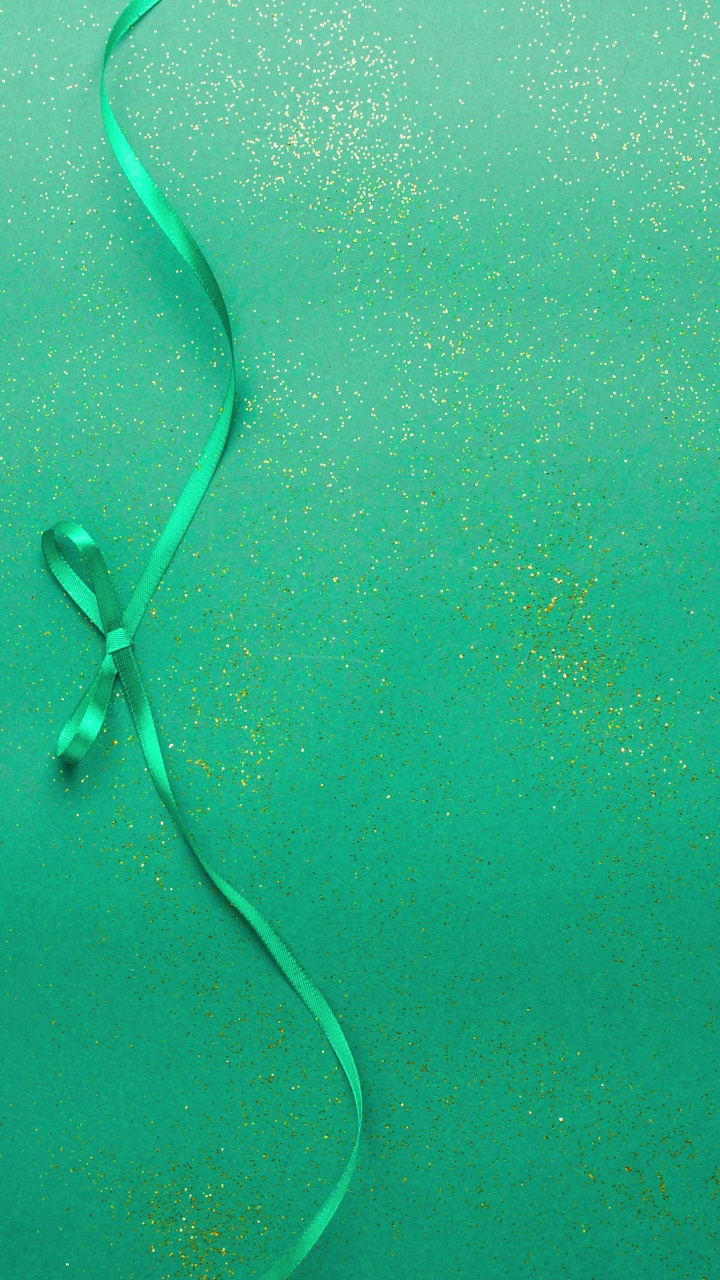 翠绿色缎带蝴蝶结，系和解开的绿色与金色闪光。定格动画垂直圣诞假期和呈现概念平面铺设与复制空间视频下载